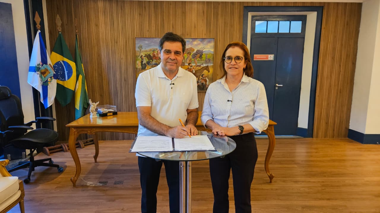 A foto mostra o prefeito Evandro Leitão e a secretária da Saúde Riane Azevedo no gabinete dele, o prefeito está assinando a lei